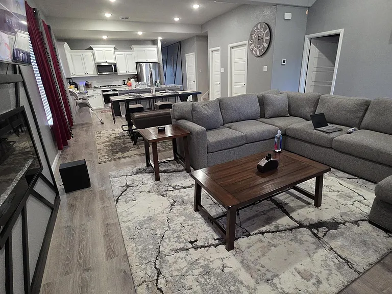 Open-concept living area with a large sectional, coffee table, and easy flow into the kitchen with bar seating.