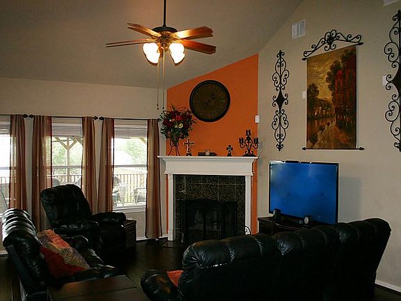 Den has a high ceiling with a granite-surround fireplace and recent wood floors.
