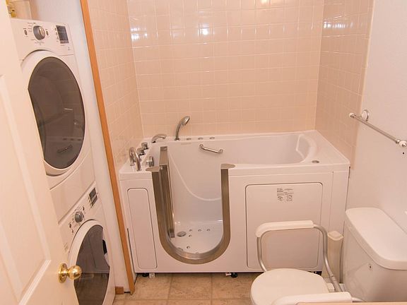 Walk-in jacuzzi tub with colored lights, stacking washer and dryer and large cabinet for supplies