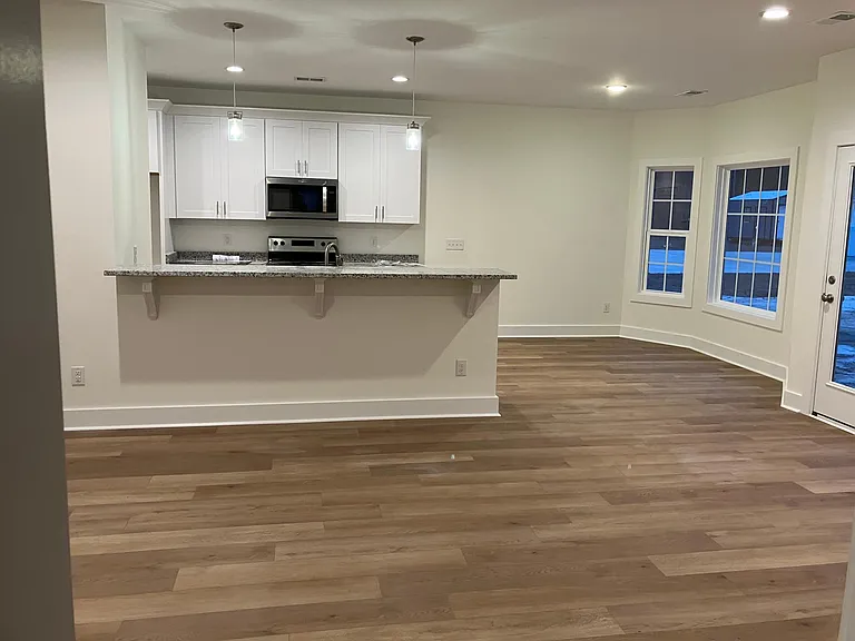 Partial view of kitchen and serving bar from family room. This house has a Whirlpool refrigerator and floor to ceiling built in pantry, not visible in this picture.