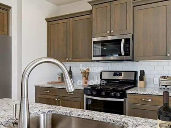 Beautiful kitchen with durable quartz countertops, stainless steel appliances, a large basin sink, and a refrigerator.