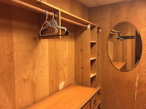 LEFT SIDE OF BIG WALK-IN CLOSET WITH CHEST OF DRAWERS, SHELVES, AND MIRROR