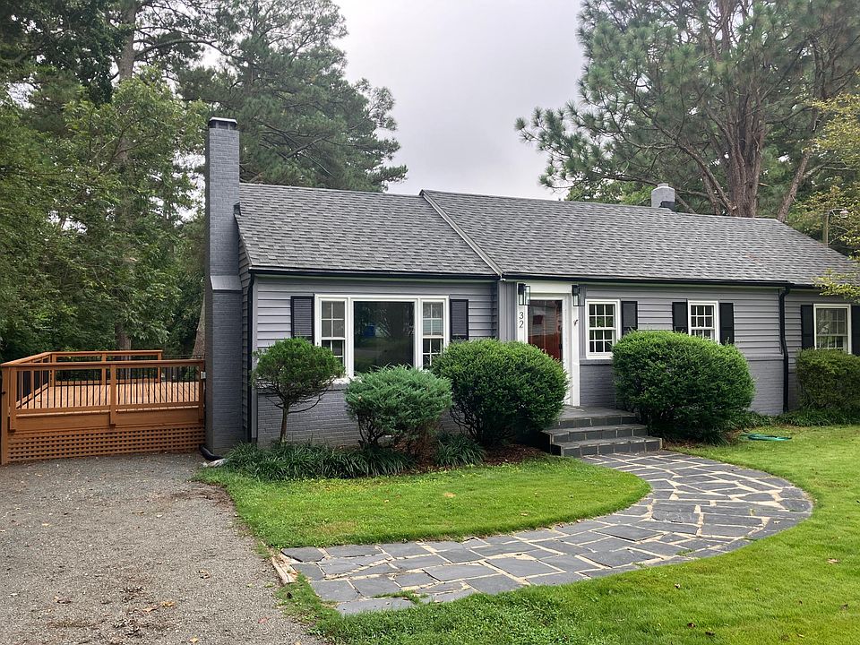 Front of home with large side deck, gravel driveway, slate walkway