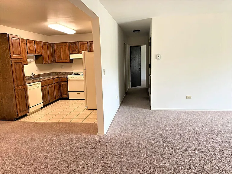 Living room/Dining area with carpet. Kitchen with white appliances (Carpeted Unit)