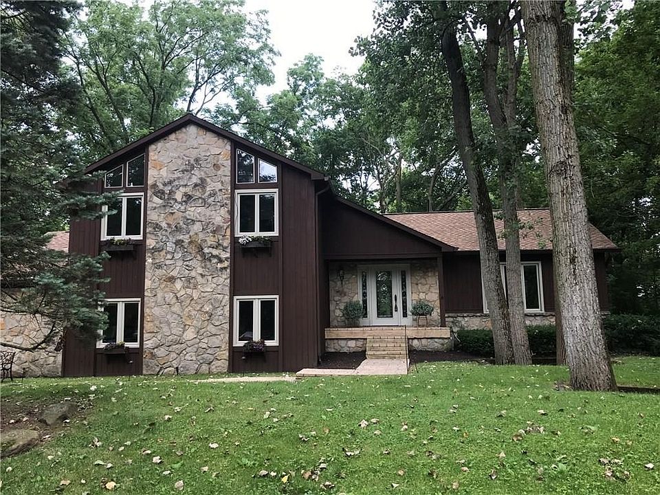 Charming tri-level home with stone, large windows, flower boxes and surrounded by beautiful mature trees.