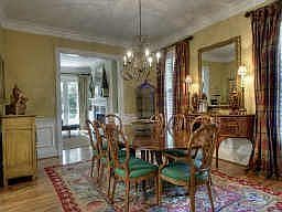Spacious dining room has wainscoting, hardwood floors, plantation shutters, custom draperies.