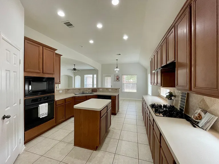 Functional kitchen with center island, ample cabinet space, pantry, and breakfast bar.