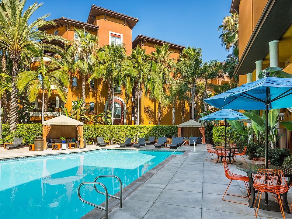 Resort-style pool with lounge chairs and covered tables