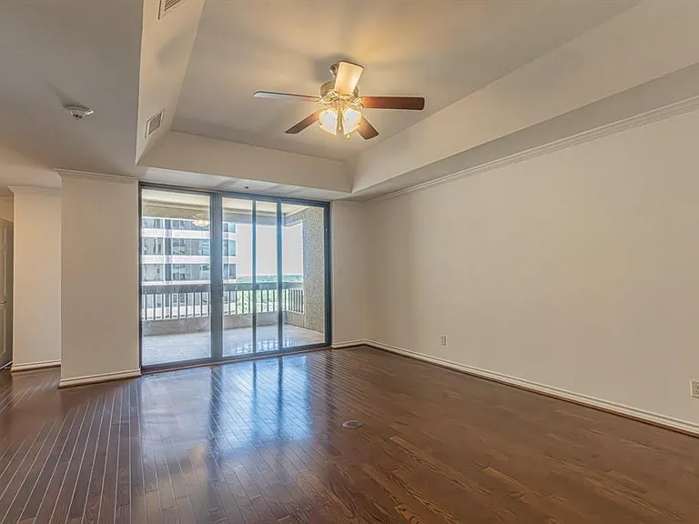 Expansive room featuring rich wood-finish flooring and a ceiling fan