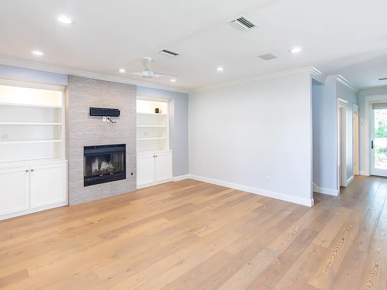 Open concept living room with built in bookshelves and a fireplace.