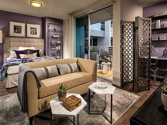 Staged bedroom with hardwood style vinyl flooring and sliding door to balcony.