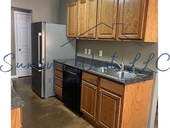 Galley kitchen with stainless, bottom-freezer refrigerator.