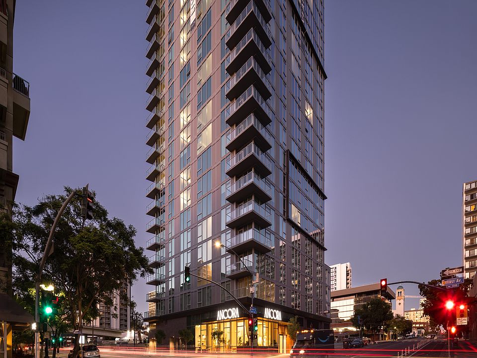 Stunning high-rise apartment building with modern glass architecture, illuminated warmth from within, offering urban living in a vibrant cityscape setting.