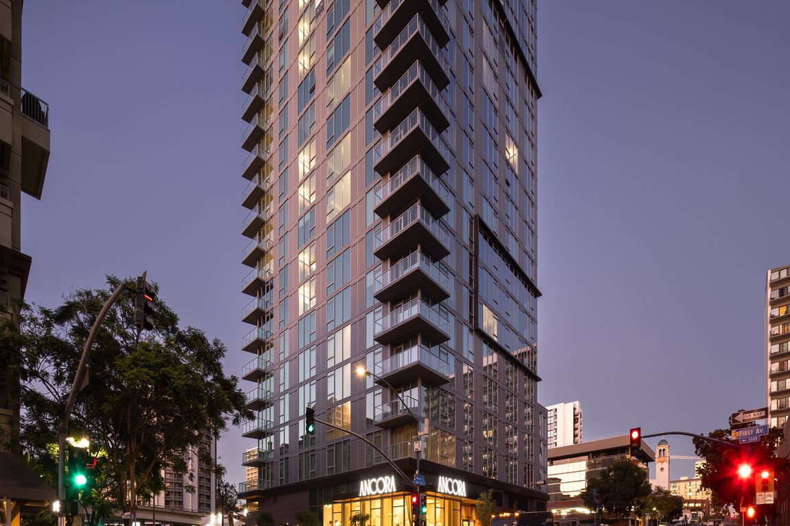 Stunning high-rise apartment building with modern glass architecture, illuminated warmth from within, offering urban living in a vibrant cityscape setting.