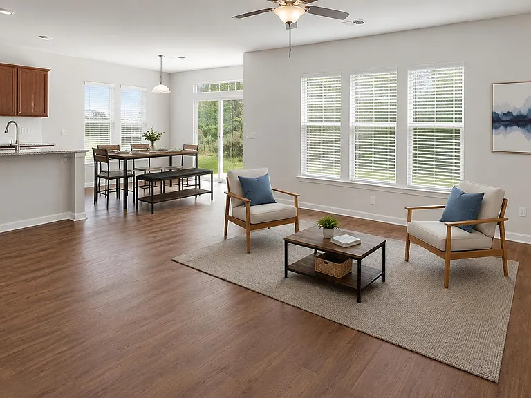 Open-concept living area with wood-style floors, large windows, and seamless flow to the dining space and kitchen.