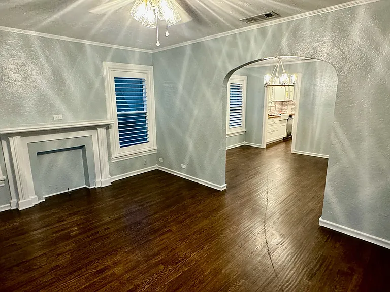 View from the private porch, looking into the dining room with feaux fireplace, beautiful hand scraped hard wood floors and plantation wood shutters and into the dining room and kitchen.