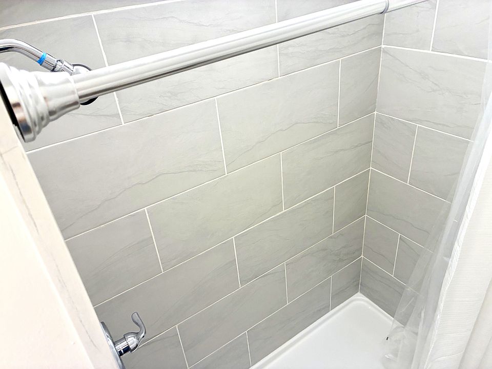 Newly tiled walk-in shower with modern gray subway tile and chrome finishes.