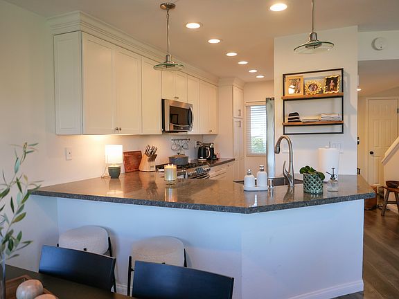 Remodeled kitchen open to living space with newer quartz countertops and bar seating