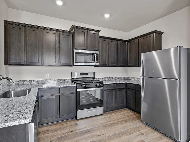 The kitchen has wood cabinetry and sprawling granite countertops.