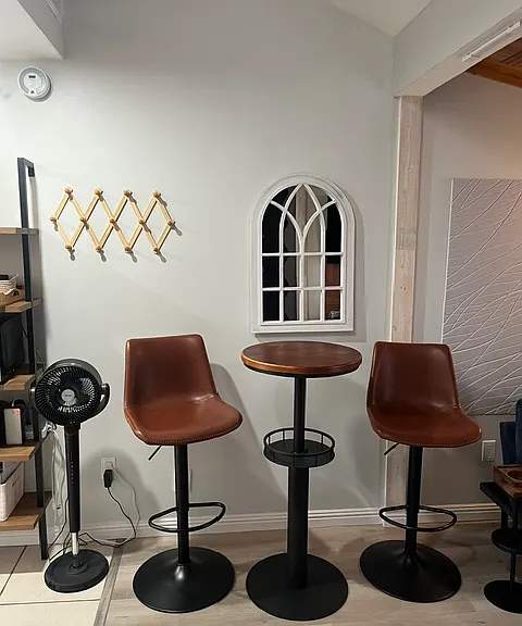 Oscillating floor fan with barstools and table.