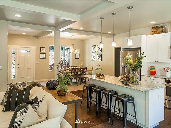 Looking from the far side of the home toward the front door and dining room. Quartz countertops in the kitchen. Pendant Lights are an upgrade. Engineered Hardwood floors are an upgrade. PHOTO OF SIMILAR HOME ALREADY BUILT>