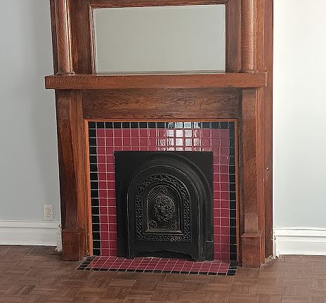 Living room with original wooden mantle and non functioning fire place. Original tile work.