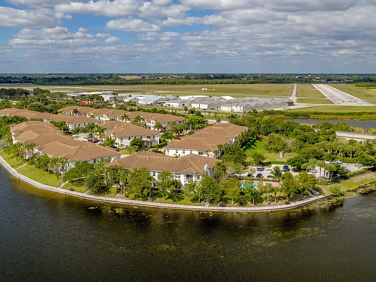 Aerial view of elegant lakeside apartments with charming terracotta roofs surrounded by lush greenery and scenic water views, enhancing a serene lifestyle.