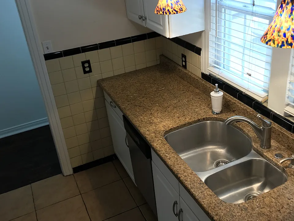 Kitchen showing stainless steel sink and dish washer. Sink fixture has a retractable spray handle.