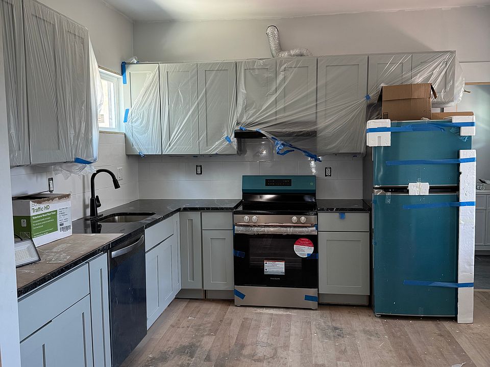 Grey cabinets and stainless steel appliances with a black granite counter. The fridge is not blue. its the protective coating on it.