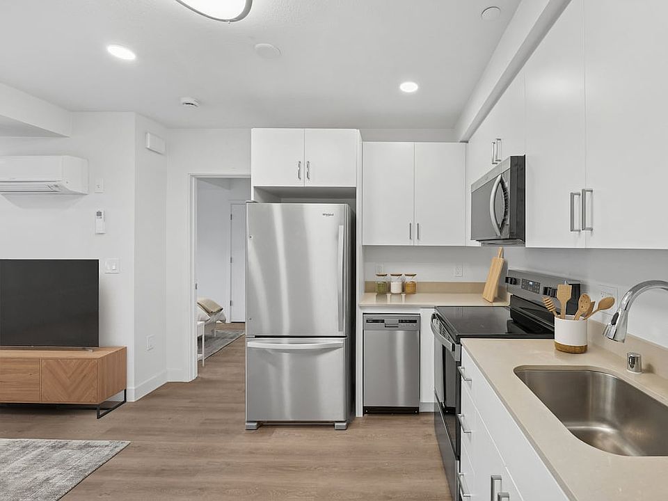Renovated Package kitchen with stainless steel appliances, beige quartz countertops, white cabinetry, and hard surface flooring
