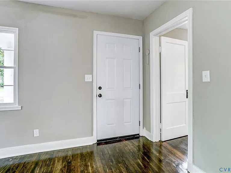 A view of the front door entrance into the living room. The door to the right is the front facing bedroom
