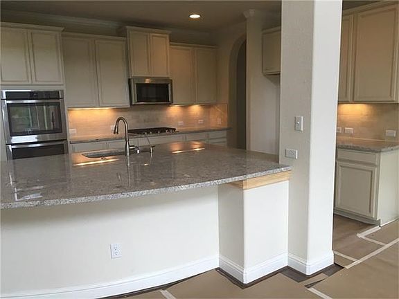 Large kitchen island accentuated with upgraded granite. Beautiful stone backsplash with under cabinet lighting!