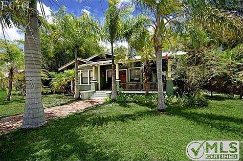 Classic Craftsman architecture featuring cross gable roof with wide overhands and exposed rafter tails, wide wrap-around porch with square tapered balusters and original diamond patterned windows