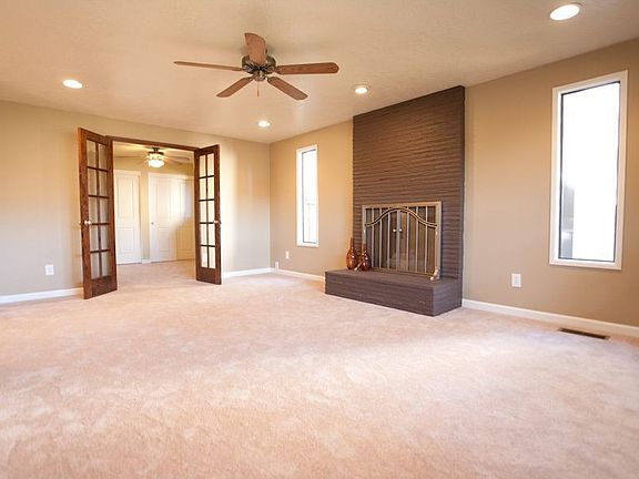 Living room with gas fireplace, ceiling fan and french doors to den or 4th bed