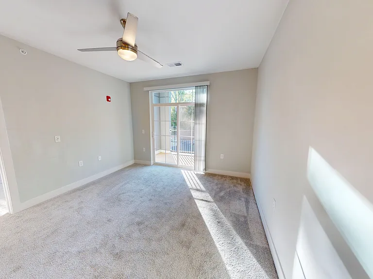 The Elm's open-concept floor plan includes a carpeted living room with sliding glass door to the private patio or balcony. The Elm's open-concept floor plan includes a carpeted living room with sliding glass door to the private patio or balcony.