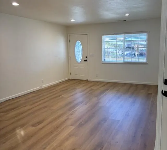 First view of newly renovated Living Room with new flooring, paint, light features and window covering.