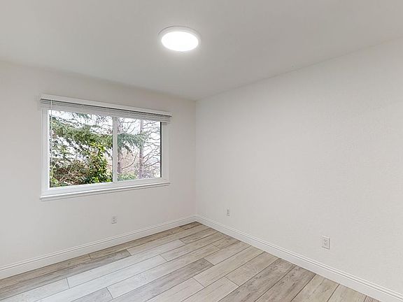 Sunlit room with a large window and wood-like flooring