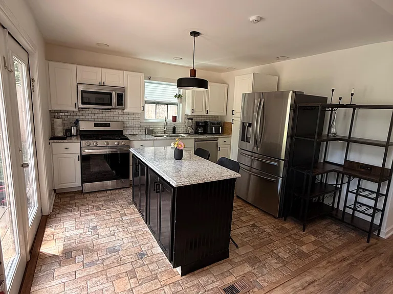 Updated kitchen with granite island, stainless appliances, ample cabinetry, and a window over the sink for easy meal prep.