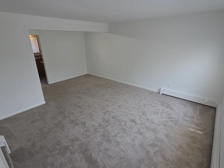 Bright living room with new carpeting and flexible furniture arrangement.
