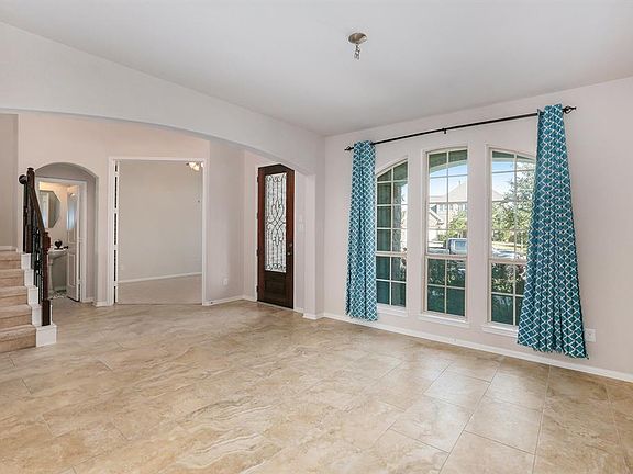 Upon entry, you'll find extensive tiled flooring and a stunning wrought iron staircase. This photo was taken from the formal dining room looking toward the study and 1/2 bath just past the stairs.