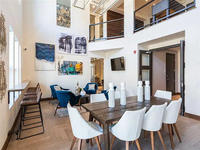 Bright resident lounge with table, bar, and coffee table seating