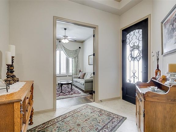 Handsome solid wood, iron and glass door leads to tiled foyer with trey ceiling and crown molding. Study-den straight ahead.
