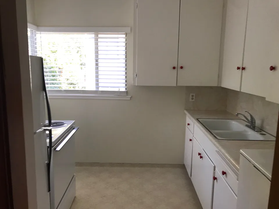 Light and airy kitchen with sunken porcelain sink, stove, oven, fridge and freezer, and additional storage / cupboards
