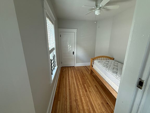 Small bedroom with walk in closet and refinished hardwood floors.