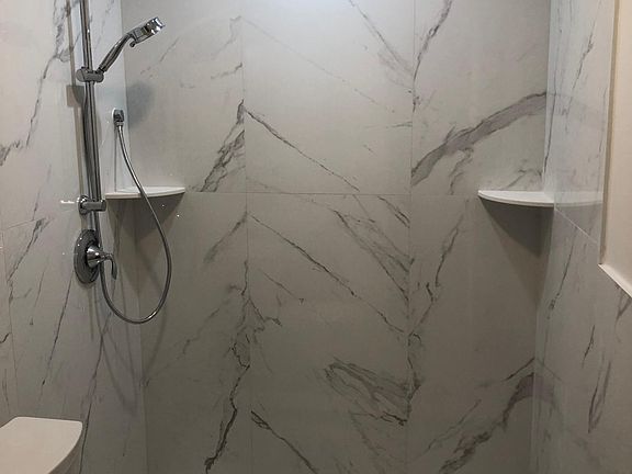 Luxurious handsome walk-in shower. Modern metropolitan style with invisible grout lines, large tiles, built for easy care and clear glass wall.