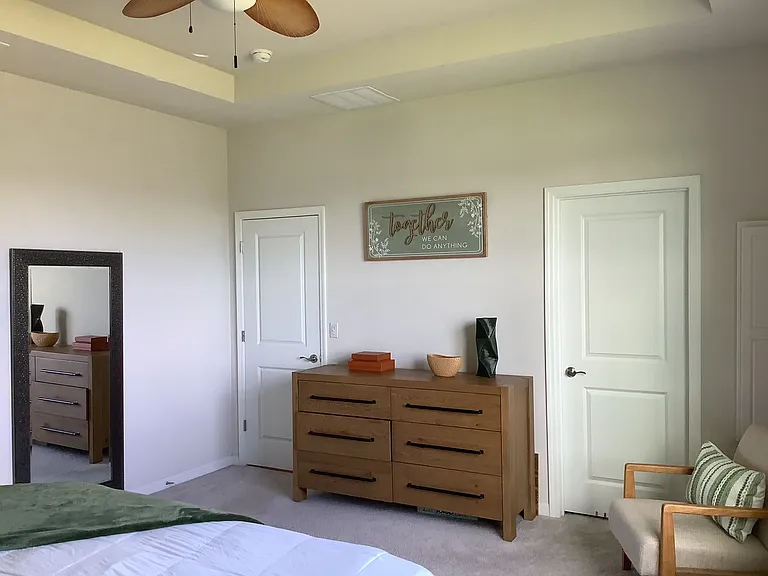 Primary bedroom, convenient walk in closet, full length dressing mirror, built in ironing board and ceiling fan