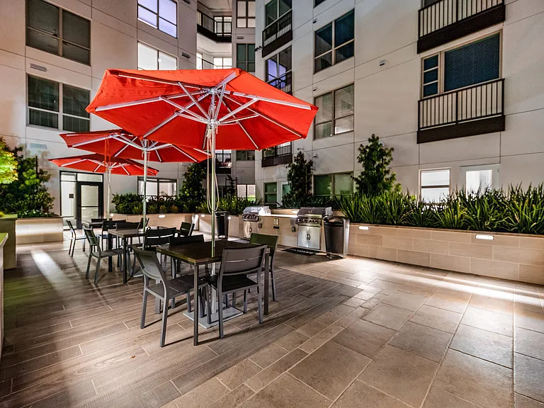 Outdoor dining area with grills, red umbrellas, and seating