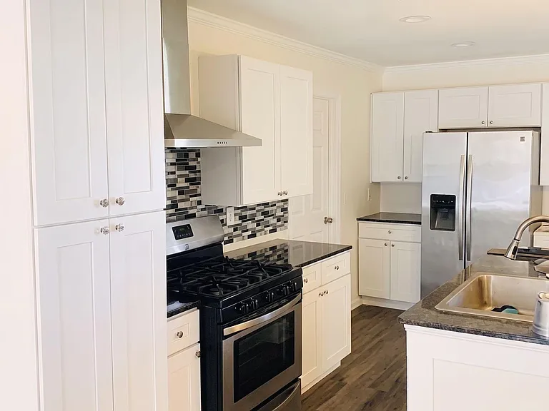 Well-appointed kitchen with ample shaker cabinetry, mosaic tile backsplash, and stainless steel appliances plus breakfast bar