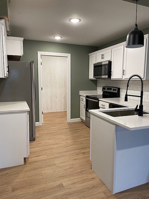 Kitchen featuring luxury vinyl plank, quartz countertops and stainless steel appliances. Laundry room attached.
