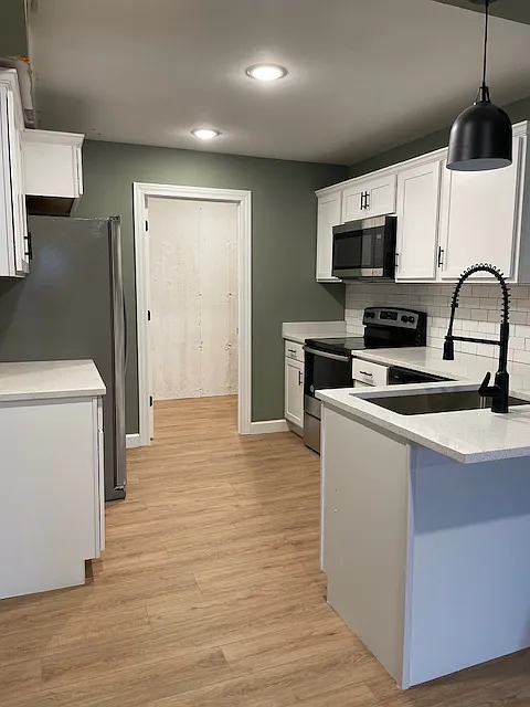 Kitchen featuring luxury vinyl plank, quartz countertops and stainless steel appliances. Laundry room attached.